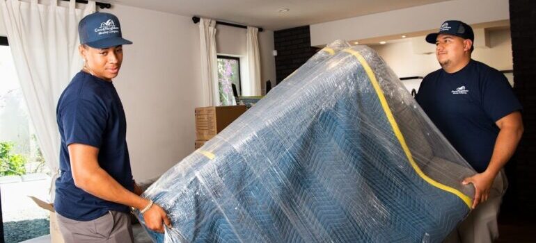 Two people working for one of the best moving companies Los Angeles County has to offer lifting a piece of furniture